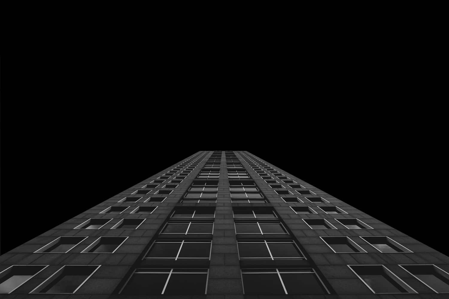 Architecture moderne noire d'un immeuble à multiples étages qui illustre la hauteur, l'ambition et les étapes à franchir.