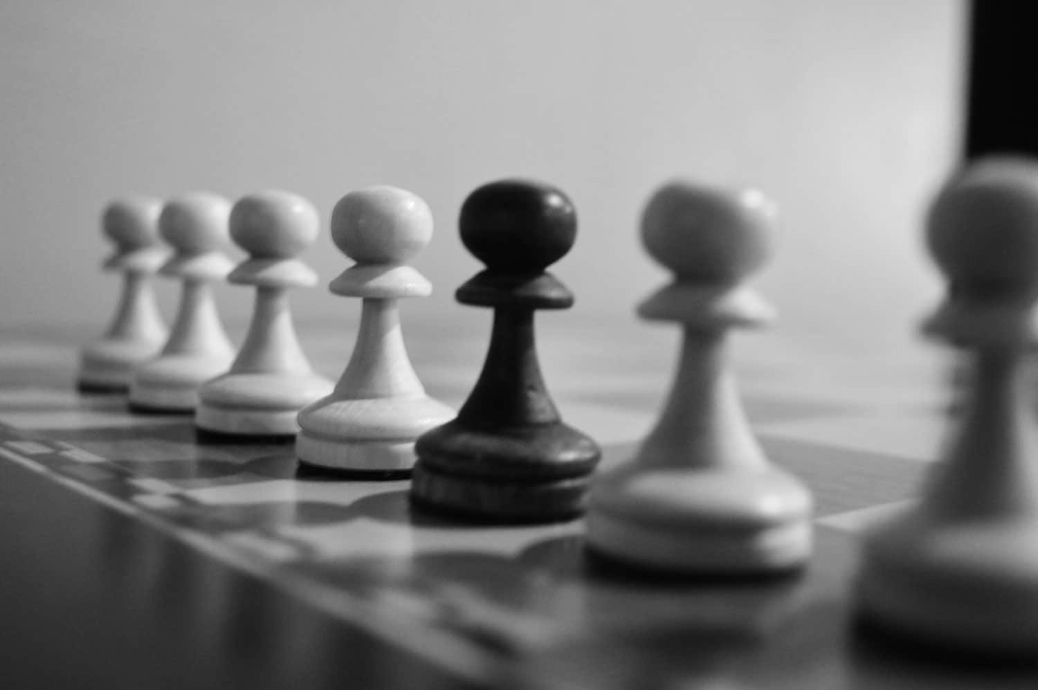 Jeu d'échec en noir et blanc avec 7 pions alignés représentant les points clés du manifesto d'incubator Studio.